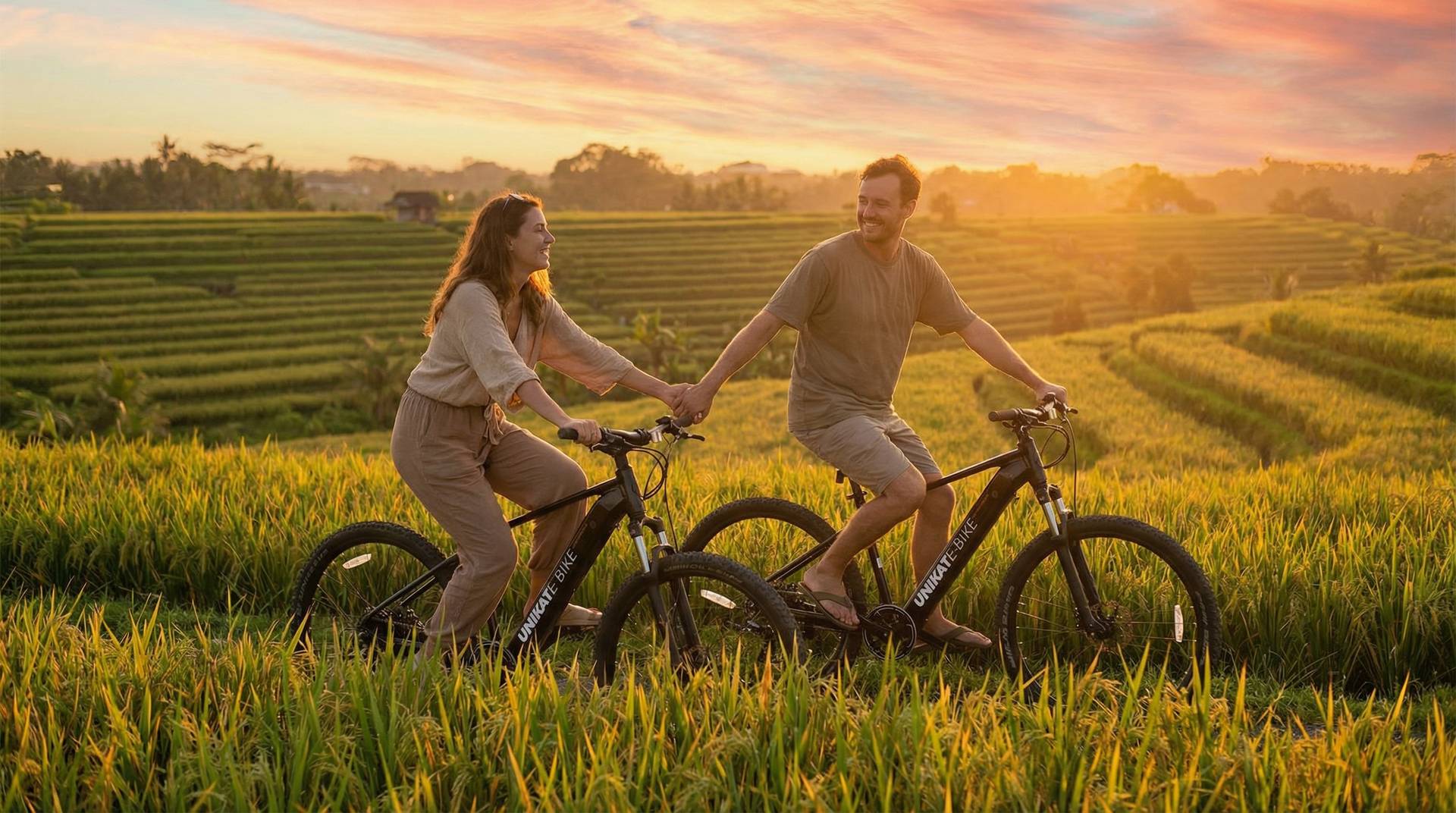 Couple riding UNIKAT e-bikes together along the Bali coast at golden hour