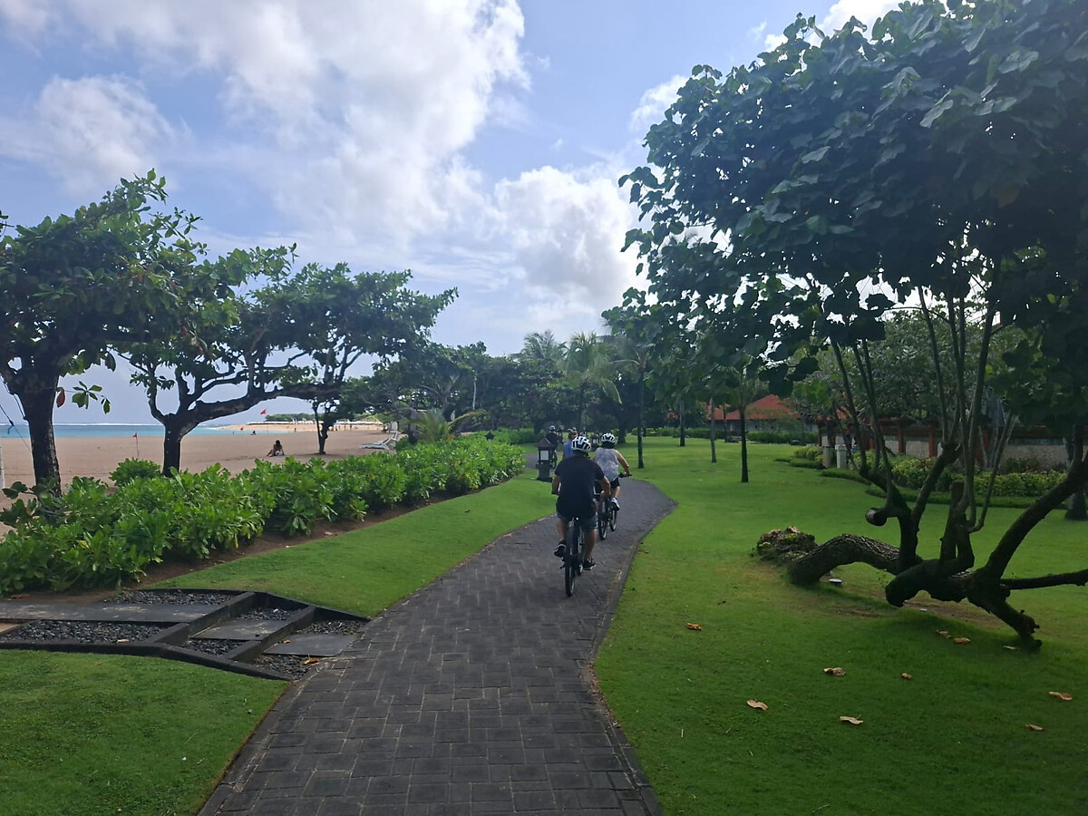 Cyclists riding e-bikes along the scenic Nusa Dua beachfront path